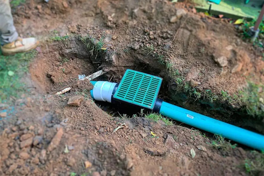 French drain installation in Austin TX yard showing underground pipe and catch basin for lawn drainage solutions