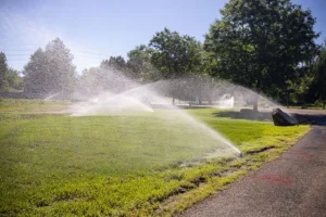 Sprinkler irrigation system watering a green lawn during summer in Austin, TX to maintain healthy grass and efficient irrigation zone coverage